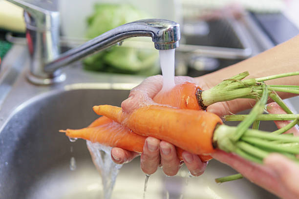istock Woman hands washing fresh orange carrots in a kitchen 2225813089