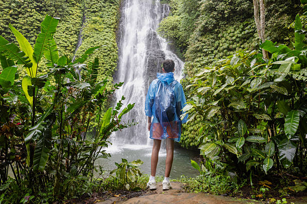 istock Rear View Of Man Standing Against Waterfall In Forest 2225813127