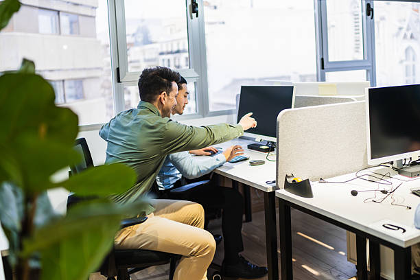 istock Young businessmen working together on computer in coworking office 2225813539