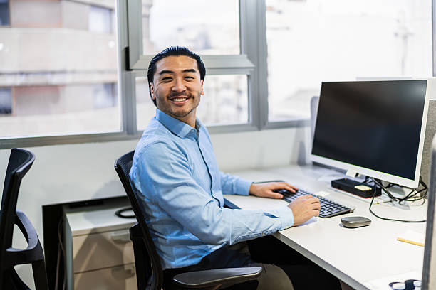 istock Young asian businessman smiling and working on computer in coworking office 2225813821