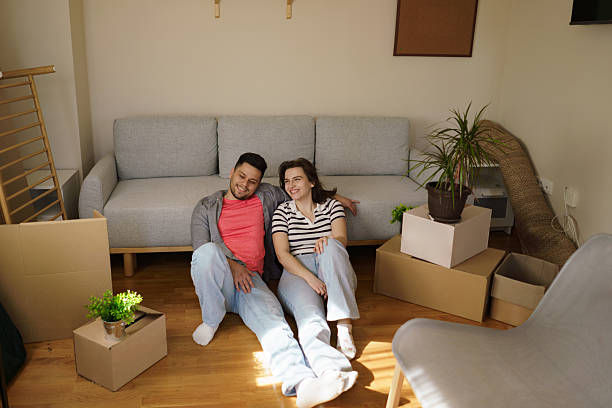 istock Happy couple sits on the floor, leaning against the sofa, surrounded by boxes. 2225814123