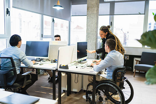 istock Young professionals collaborating in modern coworking space with disabled colleague 2225818534
