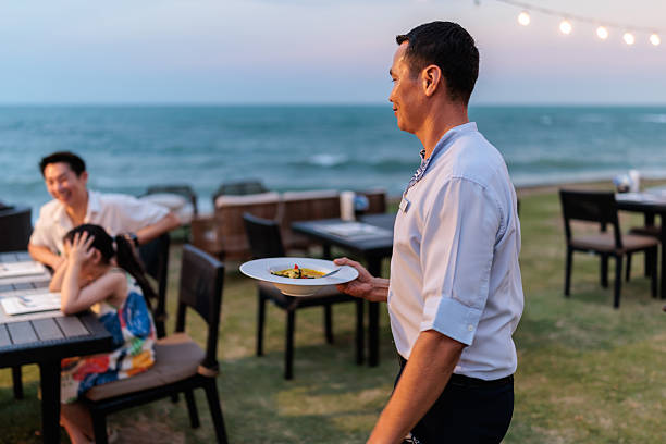 istock Waiter serving food to guests at seaside restaurant 2225818656