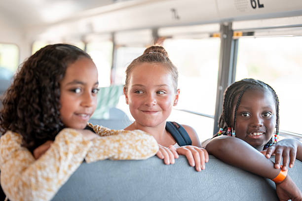 istock Three Smiling Children Sitting Together on a School Bus 2225818910