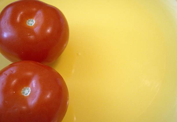 istock Two whole tomatoes on yellow plate close up. 2225819686