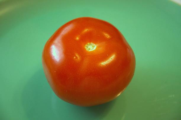 istock One whole red tomato with green background 2225820088
