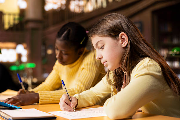 istock Multiethnic scholars doing their homework at a library desk after classes 2225821144