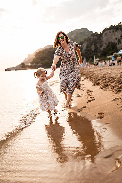 istock Mother and Daughter Barefoot Walk on the Beach 2225821884