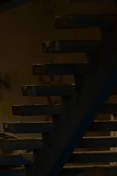 istock A person cautiously walks down stairs in a dark, shadowy room 2225825173