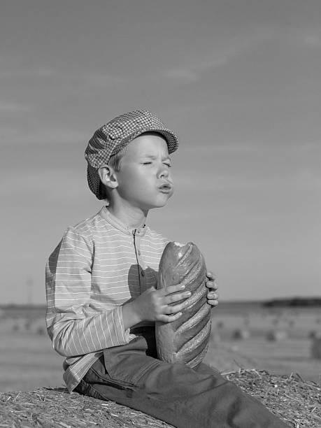 istock Boy holding bread on hay bale, black and white 2225832819