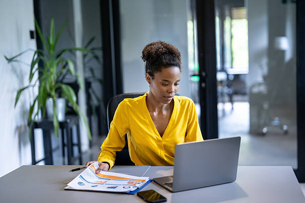 istock Focused young businesswoman analyzing charts and working on laptop in modern office 2225833372