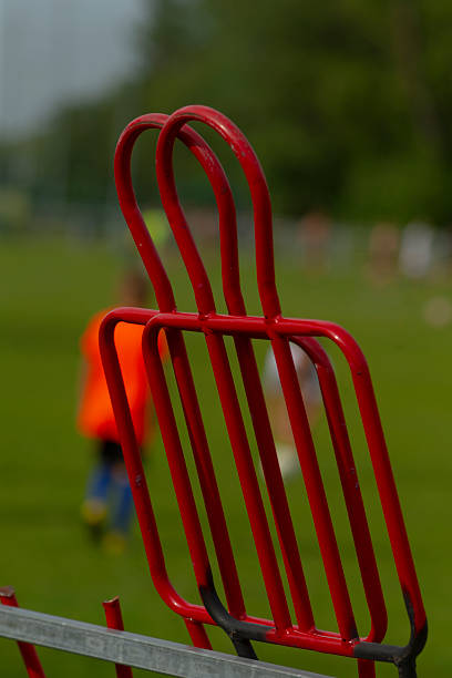 A striking red fence stands tall while a person walks in the background
