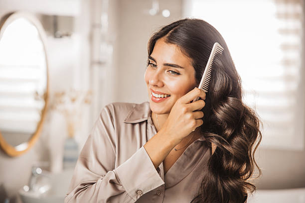 Young woman combing hair in front of mirror.