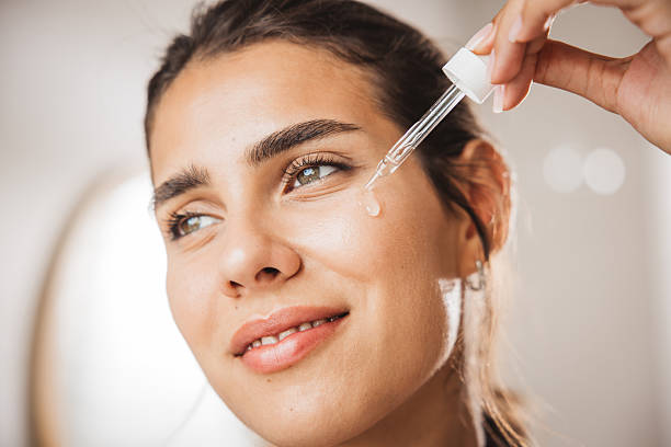Young woman applying serum on face