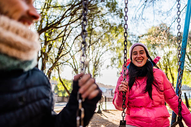 istock Mid adult couple talking while swing at outdoors playground 2225835240
