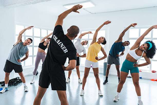 istock Trainer guiding group of athletes stretching in gym during functional training workout 2225837623