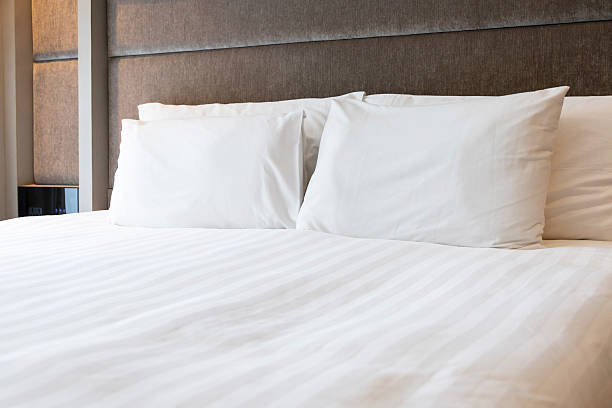 istock Bright clean comfortable bedroom interior white bed linen bedding soft pillows plush duvet light window contemporary design home comfort hotel apartment space. 2225837758