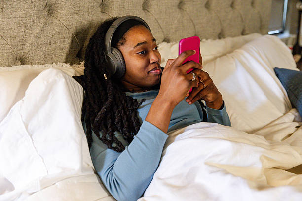 istock Relaxing Woman in Bed Using Smart Phone and Headphones 2225837867