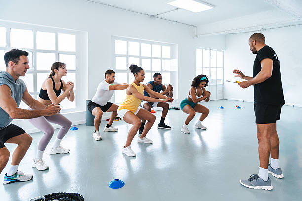 istock Group of athletes doing squats with personal trainer in gym 2225838696