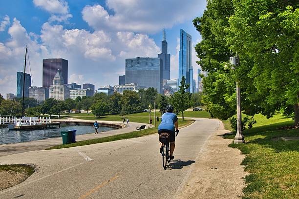 Chicago, Illinois, USA – July 15, 2025: A cyclist peddles past a harbor toward Downtown on a sunny Summer day along the Lakefront Trail in Chicago, IL.
