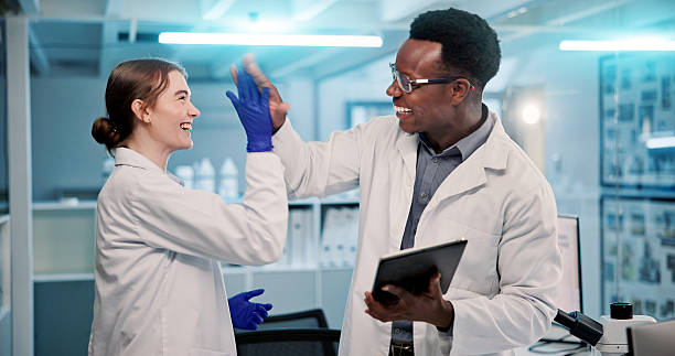 istock Science, research and people with high five, tablet or support with vaccine development. Employees, gesture or scientists in lab, biotech or medical achievement with breakthrough or email for funding 2225839516