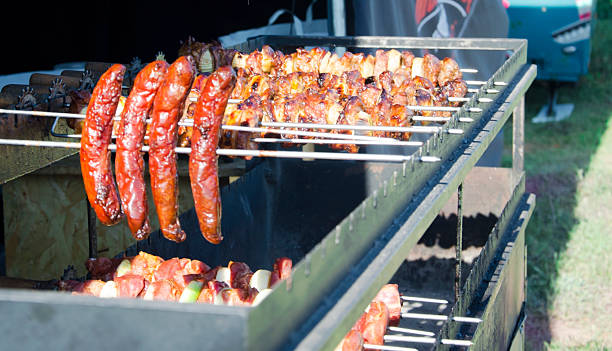 Meat on skewers and sausages are fried on the grill.Spinning barbecue for outdoor kitchen. Street restaurant.