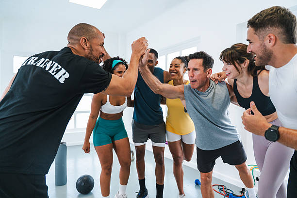 Multiethnic group of sportive people doing functional workout in training class gym cheerful athletes high-fiving their personal trainer after completing a functional training workout