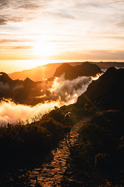istock Young man hikes stone path above bay and mountains at sunset, Madeira 2225842738