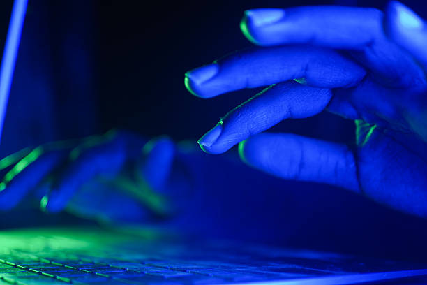istock hacker Hands typing on a laptop illuminated by blue and green light 2225844091