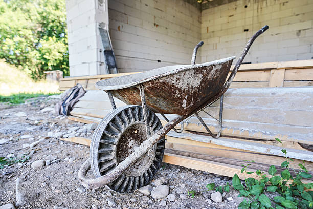 Old empty wheelbarrow at house construction site, closeup detail