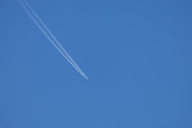 istock Airplane in a blue sky without clouds. The airplane has a flight trail behind it 2225849278