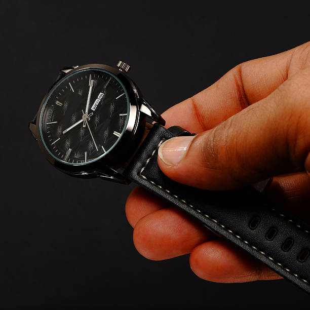 istock Black leather watch holding hand on black background close-up view 2225858859