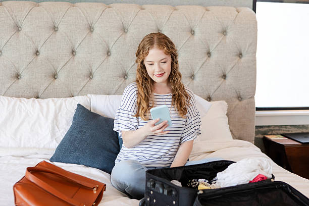 istock Young Woman Packing Suitcase, Using Smartphone, Hotel Room 2225861479