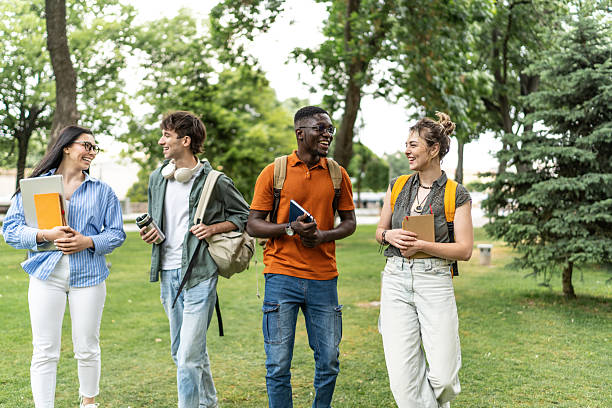 istock Cheerful university students walking and talking on campus lawn 2225861498