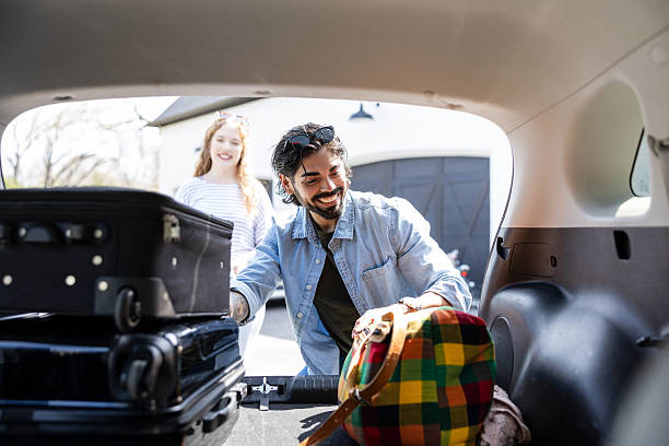 istock Couple Packing Suitcases into Car Trunk for Vacation 2225861502