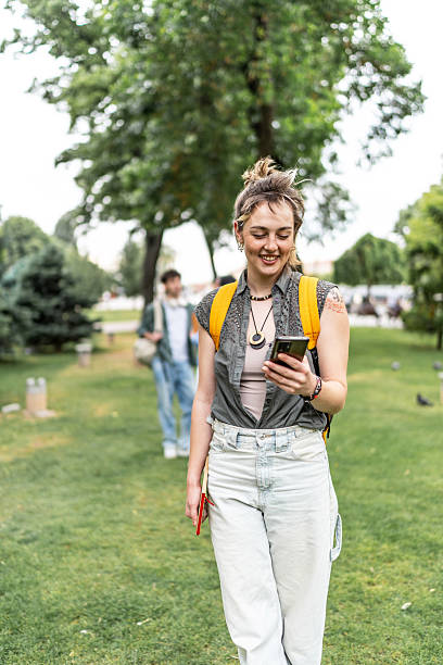 istock Young student walking in the park using her smartphone 2225861822