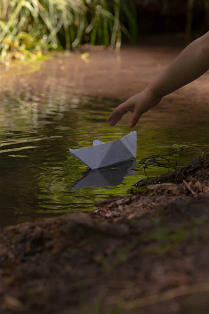 istock A person is gently throwing a small paper boat into a flowing river 2225865319