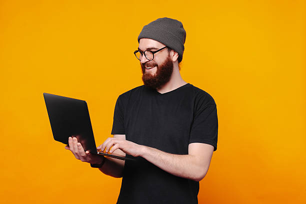 istock A Happy Young Man Working Enthusiastically on His Laptop Against a Bright Orange Background 2225866618