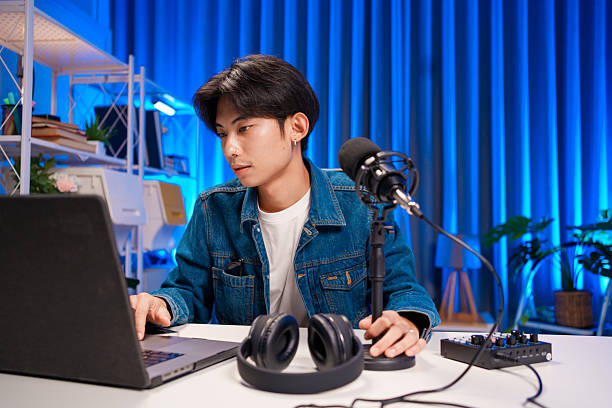 istock Young man working on podcast production with microphone and laptop in studio 2225868750