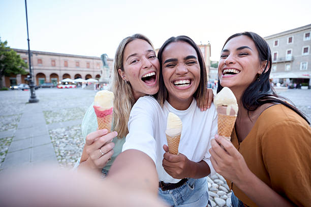 istock Three happy female friends taking a selfie while eating ice cream in a town square 2225877882