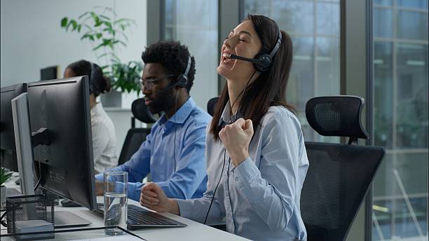 istock Callcenter success multiethnic operators work computer helpline service agency Caucasian business woman clenching fist successful online trading Indian African coworkers headset call center in office 2225883938