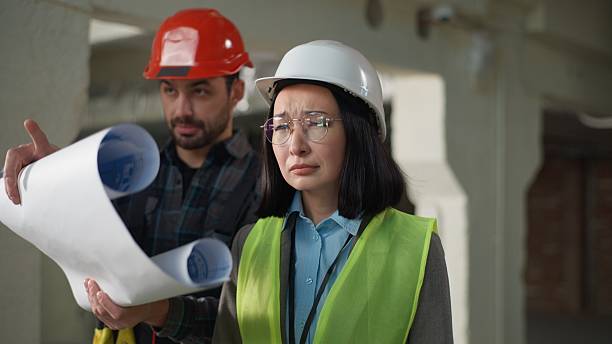 istock Building business inspection multiethnic builders architects talking blueprint at site Caucasian man engineer hold blueprint discuss Asian woman inspector unhappy surveyor failure taking off glasses 2225884020