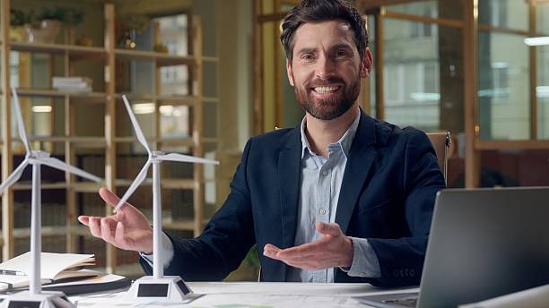 istock Confident Caucasian business green energy engineer presenting eco sources windmills at office male man businessman showing thumb up gesture laptop environment ecology wind turbine project presentation 2225885464