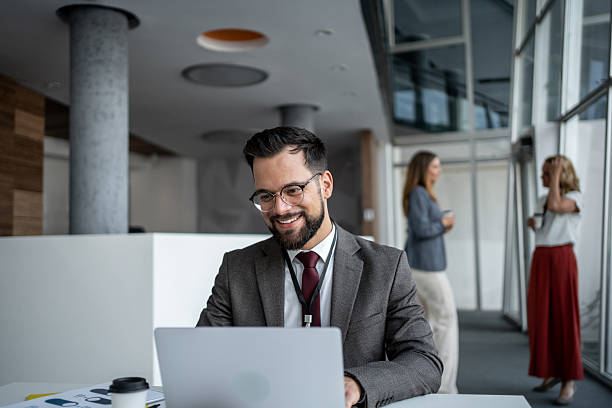 istock Businessman working on laptop in modern office with colleagues 2225889236