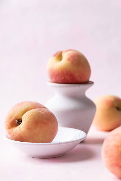 Fresh peaches in a bowl on pink background, Summer fruit