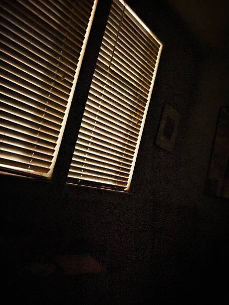 Abstract horror background for halloween. Gloomy scary terrible window with ghostly light and shadows in a dark black room in the attic, corridor or basement in an abandoned house in the forest