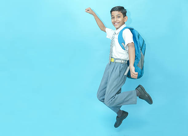 istock Excited Indian schoolboy student jumping with joy isolated over blue background, Education knowledge concept. Admission open. 2225910310