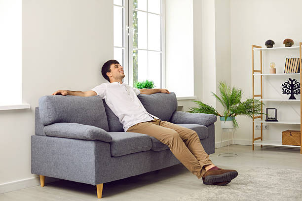 istock Satisfied calm young man resting after hard day's work sitting on comfortable sofa at home. 2225910465