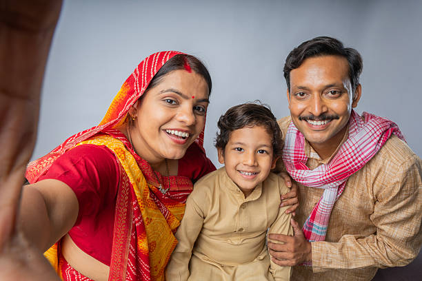 Portrait of cute boy embracing smiling mid adult parents and taking selfie while standing together against white background
