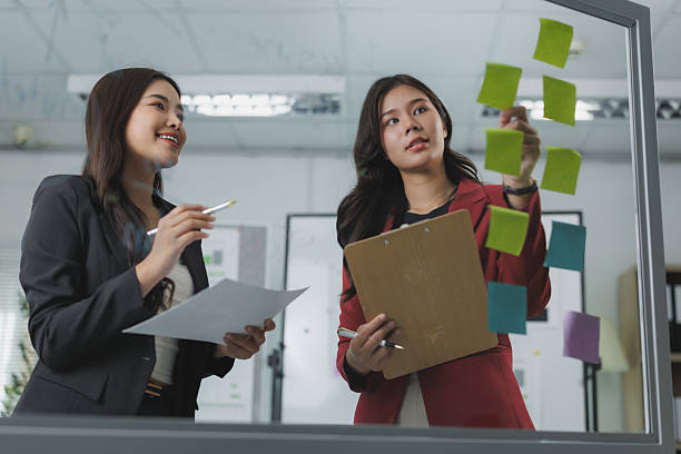 istock Businesswomen planning strategy using sticky notes on glass wall in office 2225918806